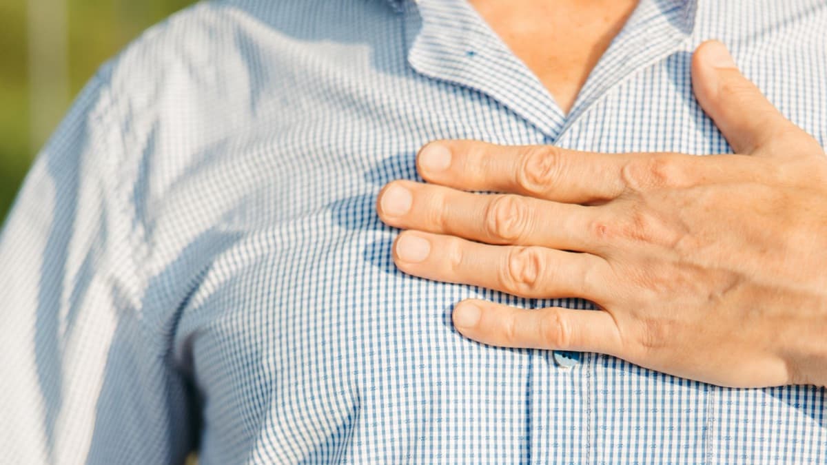 Man with his hand pressed to his chest in discomfort