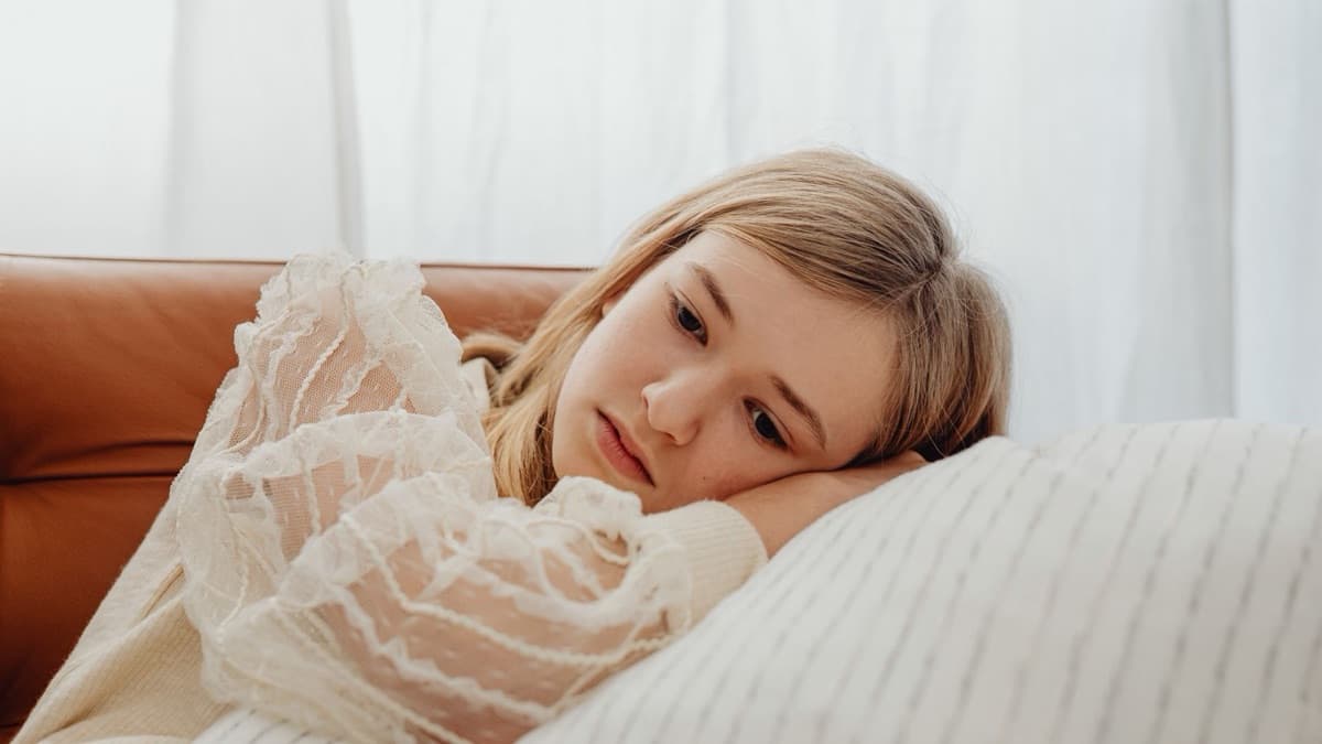 Teenage girl resting on a sofa, looking tired and withdrawn