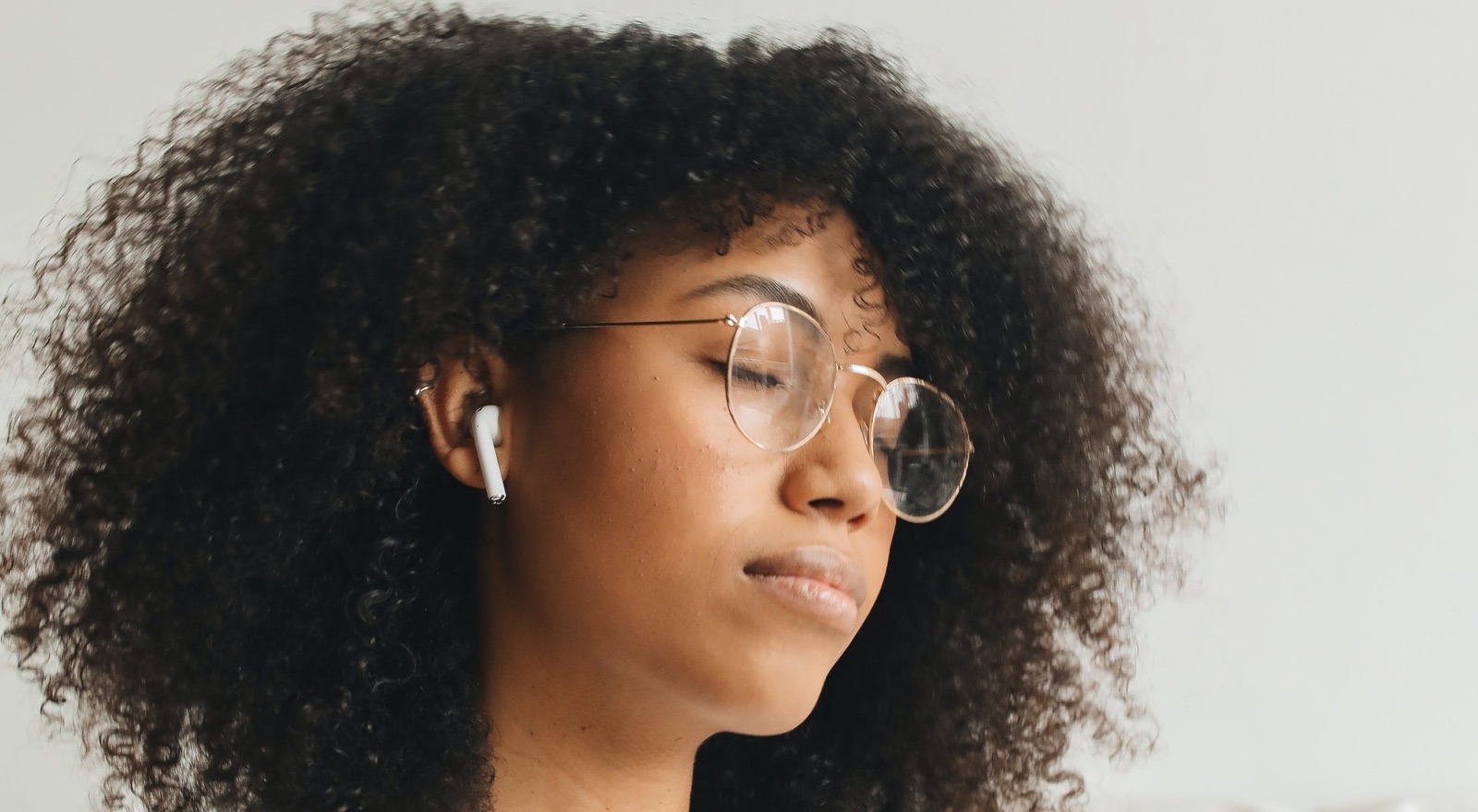 A woman resting with her eyes closed, listening through earbuds